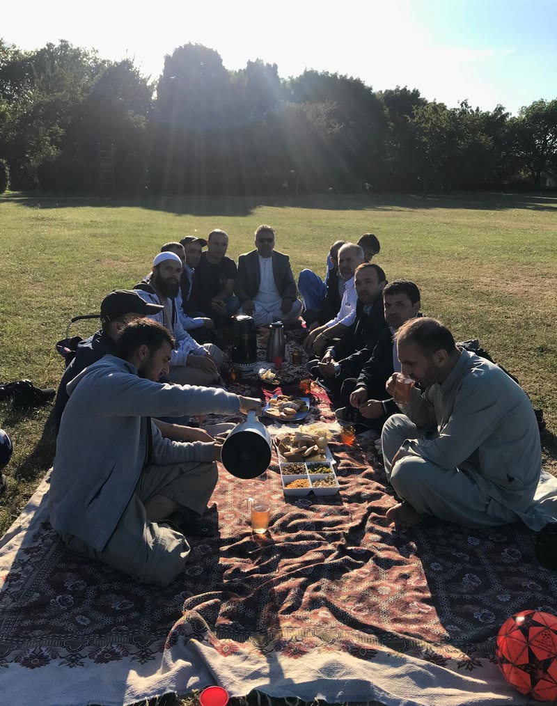 Community members sharing tea and food at a picnic in the park